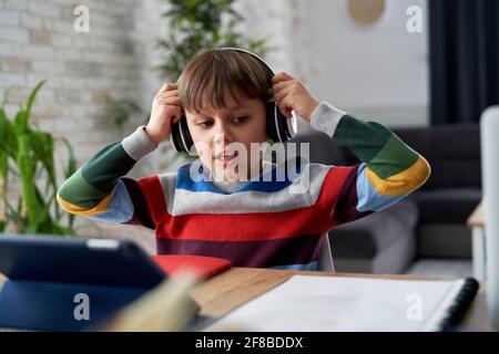 Boy in headphone during while studying at home Stock Photo