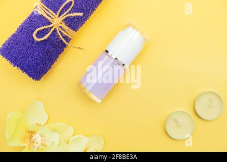 Aromatic candles, towel and lotion on a yellow background. Top view, copy space. Spa concept, flat lay. Stock Photo