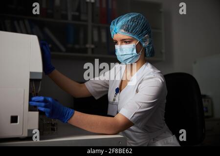 Concentrated biochemist in a face mask using a biochemical apparatus Stock Photo