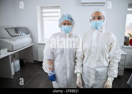 Two serious scientists in hazmat suits standing in the research lab Stock Photo