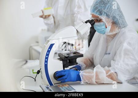 Researchers observing a blood sample mounted on the glass slide Stock Photo