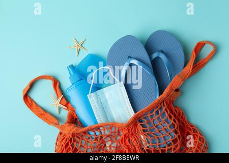 Bag with sea accessories, sunscreen and mask on blue background Stock Photo