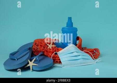 Bag with sea accessories, sunscreen and mask on blue background Stock Photo