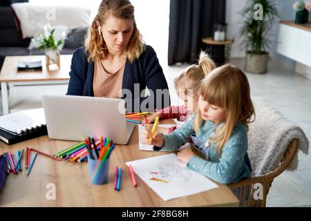 Busy mother working at home with her daughters Stock Photo