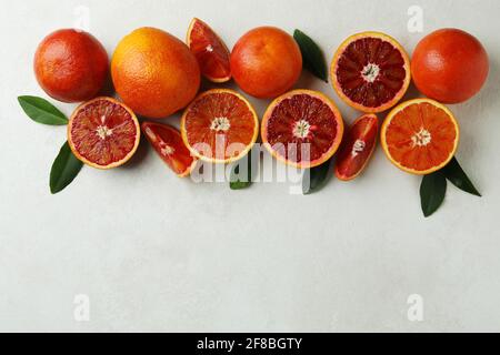 Red oranges and leaves on white textured background