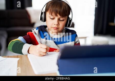 Schoolboy in headphone during homeschooling Stock Photo