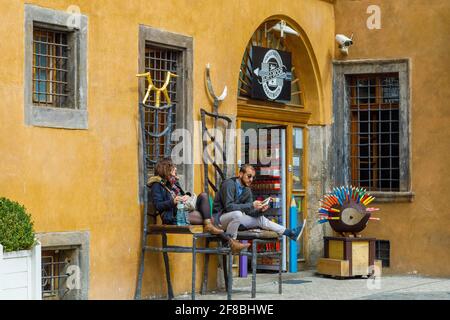 A girl and a guy are sitting on large chairs at the entrance to the pencil store. Prague, Czech Republic April 14, 2018 Stock Photo