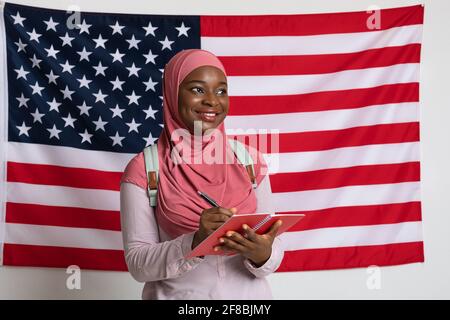 Cute black woman in hijab taking notes over american flag Stock Photo