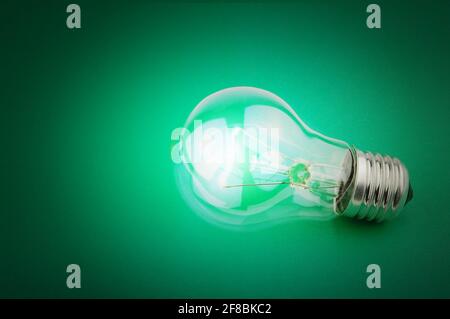 Electric light bulb on a green background. Switch on. Concept of wireless power transmission. Concept of idea and inspiration. Stock Photo
