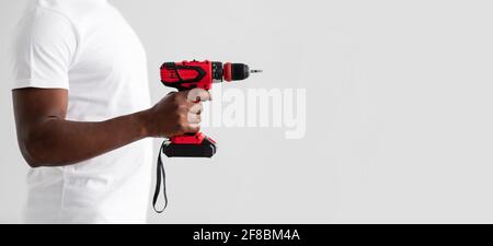 Unrecognizable black handyman holding drill or electric screwdriver, isolated on white background Stock Photo