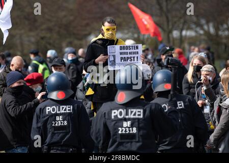 Berlin, Germany. 13th Apr, 2021. A masked demonstrator stands in front of police officers in the government quarter and protests with other people against the tightening of the infection protection law. The federal cabinet has approved the federal emergency brake. According to it, German citizens in large parts of Germany must prepare for curfew restrictions and closed shops according to nationwide binding guidelines. Credit: Paul Zinken/dpa-Zentralbild/dpa/Alamy Live News Stock Photo