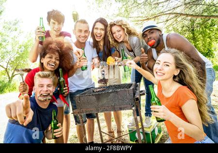 Happy multiracial friends having fun at picnic barbecue garden party - Friendship concept with multiethnic people taking group photo Stock Photo