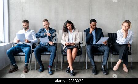 Multiethnic Applicants Waiting For Job Interview Sitting In Row Indoors Stock Photo