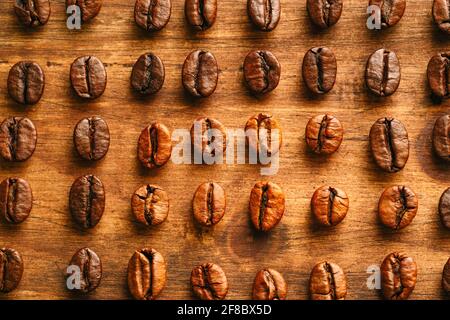 Coffee beans in a row illuminated by a window on a wooden table Stock Photo