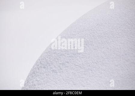 Snow curve background. Close up of snowdrift with visible texture, beautiful round shape line of pure snow wide shades of gradient. Stock Photo