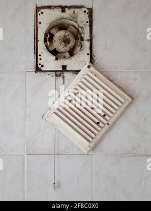 Dirty ventilation air grille with fan at home close up on white wall. Dust condition technology, dangerous old house air circulation system. Bad Stock Photo