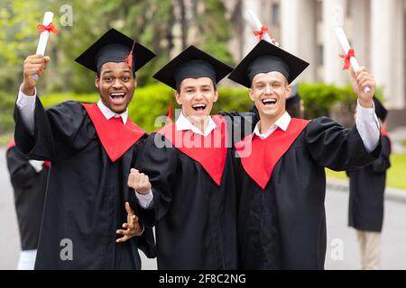 Positive guys students posing together next to university Stock Photo