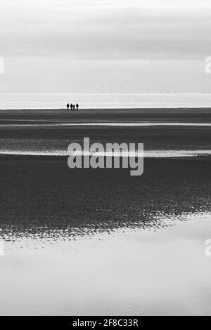 Group of four people in the distance on the beach at Holme-next-the-Sea, Norfolk, England, UK. Stock Photo