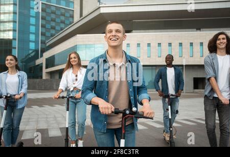 Woman having ride on motorized kick scooter with friends Stock Photo