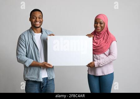 Cheerful black couple holding empty placard for advertisement Stock Photo
