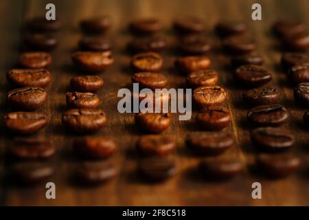 Macro view of coffee beans arranged in a row on a wooden table Stock Photo