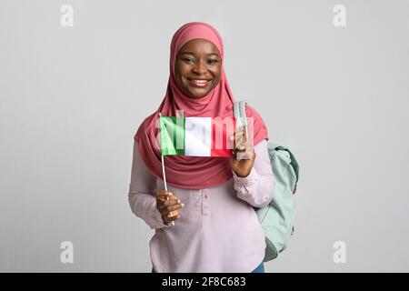 Positive black woman in hijab showing flag of Italy Stock Photo