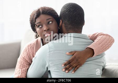 Indifferent black lady hugging her boyfriend or husband Stock Photo