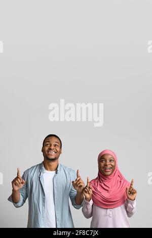 Black man and woman pointing up at empty space Stock Photo