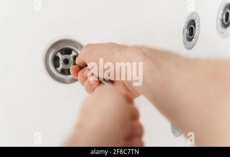 Plumber using drain snake to unclog bathtub. Stock Photo