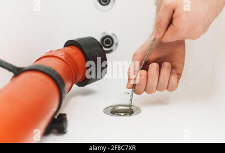 Plumber using drain snake to unclog bathtub. Stock Photo