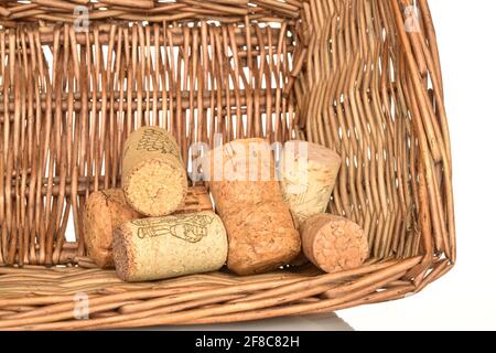 Several corks of wine, close-up, in a wicker basket, on white. Stock Photo