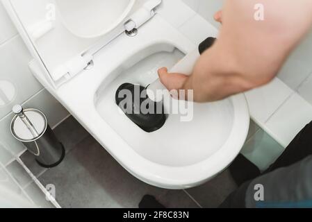 Plumber unclogging toilet with professional force pump cleaner. Stock Photo