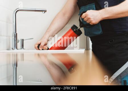 Plumber unclogging kitchen sink with professional force pump cleaner. Stock Photo