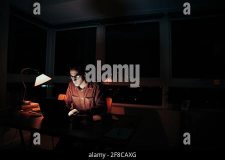 Caucasian male freelancer photographer sorting through images on laptop sitting at desk Stock Photo