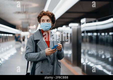 young woman reading a text message standing on a subway platform. Stock Photo