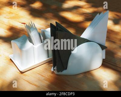 Napkin holder and salt shaker with pepper shaker and toothpicks stand on a wooden table lit by the sun's rays Stock Photo
