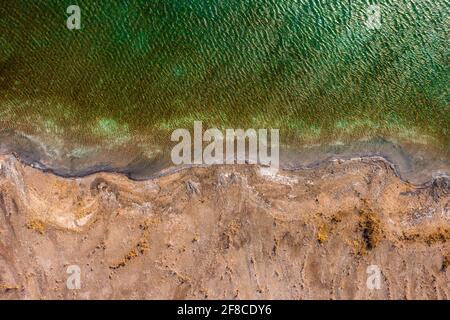 Aerial view about rocky seashore with turquoise waving water. Stock Photo