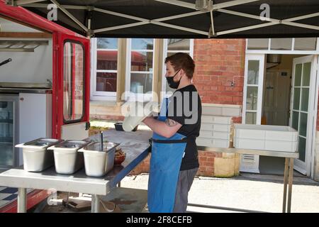 Man making pizza, throwing the dough to form the circular dough base outdoors during the covid19 pandemic Stock Photo