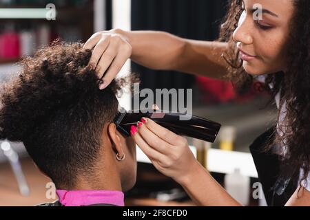African american hairdresser trimming hair of young man Stock Photo