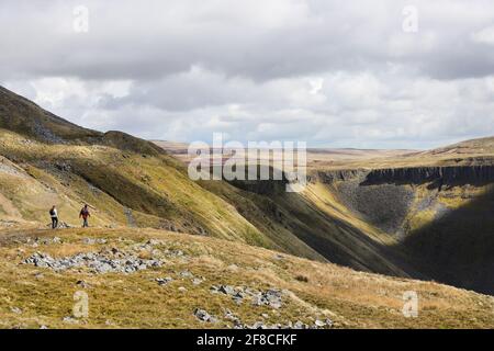 High Cup Nick, Dufton, Cumbria, UK. 13th April 2021. UK Weather.  A walker enjoys some far reaching views as she walks above the spectacular geological feature of High Cup Nick in the North Pennines as cloud builds over the Eden valley in Cumbria. Credit: David Forster/Alamy Live News Stock Photo