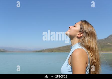 Side view portrait of a relaxed woman breathing fresh air in a lake Stock Photo