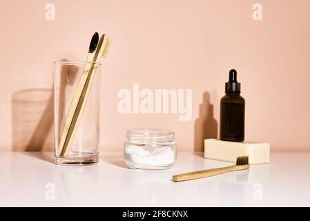Bamboo toothbrushes and tooth paste on pink background. Reuse natural products Stock Photo