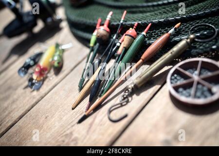 Fishing rod, reel, floats and tackle background on wooden jetty by river Stock Photo