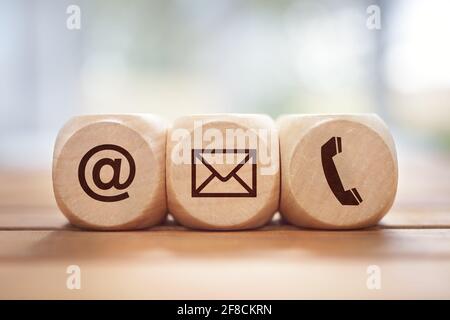 Contact us concept with wood block and symbols at, e-mail address and phone Stock Photo