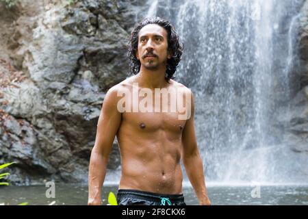 Man in front of a waterfall looking away Stock Photo