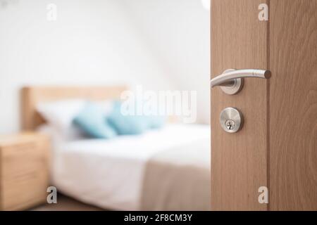 Hotel room or apartment doorway with key and keyring key fob in open door and bedroom in background Stock Photo