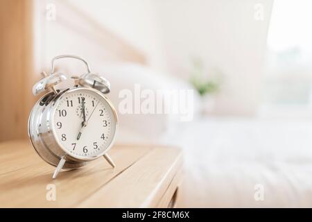 Alarm clock morning wake-up time on bedside table with copy space Stock Photo