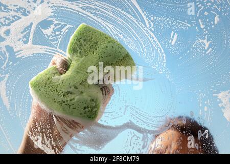 Window cleaner using a sponge to wash a window with clear blue sky Stock Photo