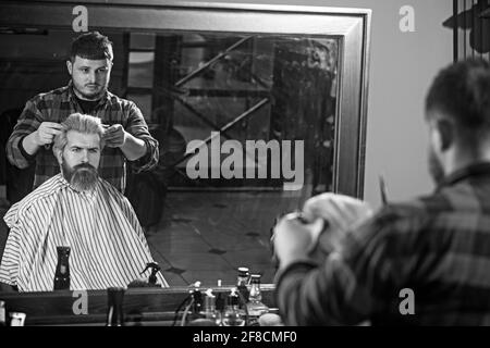 Side view of serious man with stylish modern haircut looking forward in barbershop. Stock Photo