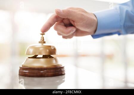 Businessman ringing a hotel reception service bell to attract attention Stock Photo